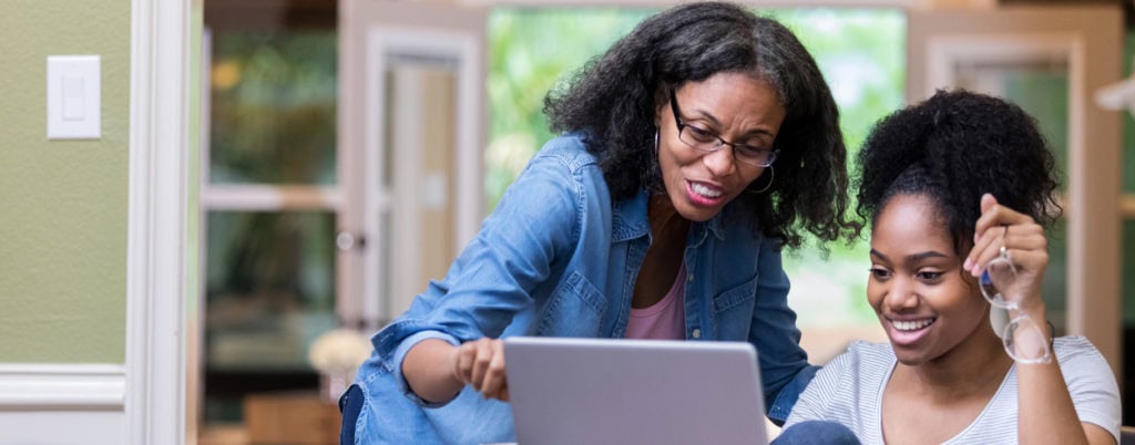 Two women looking and pointing at laptop