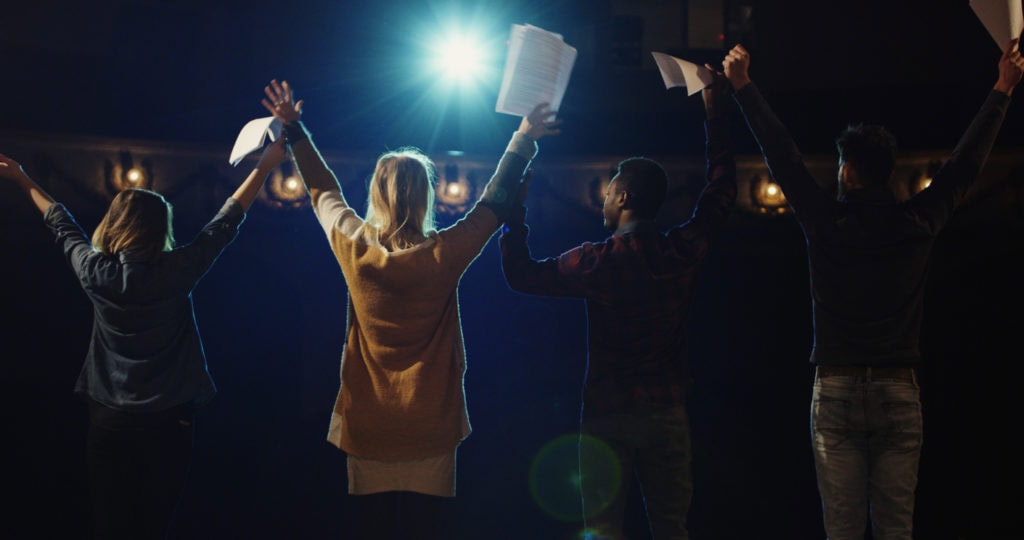 Students on stage bowing in the night