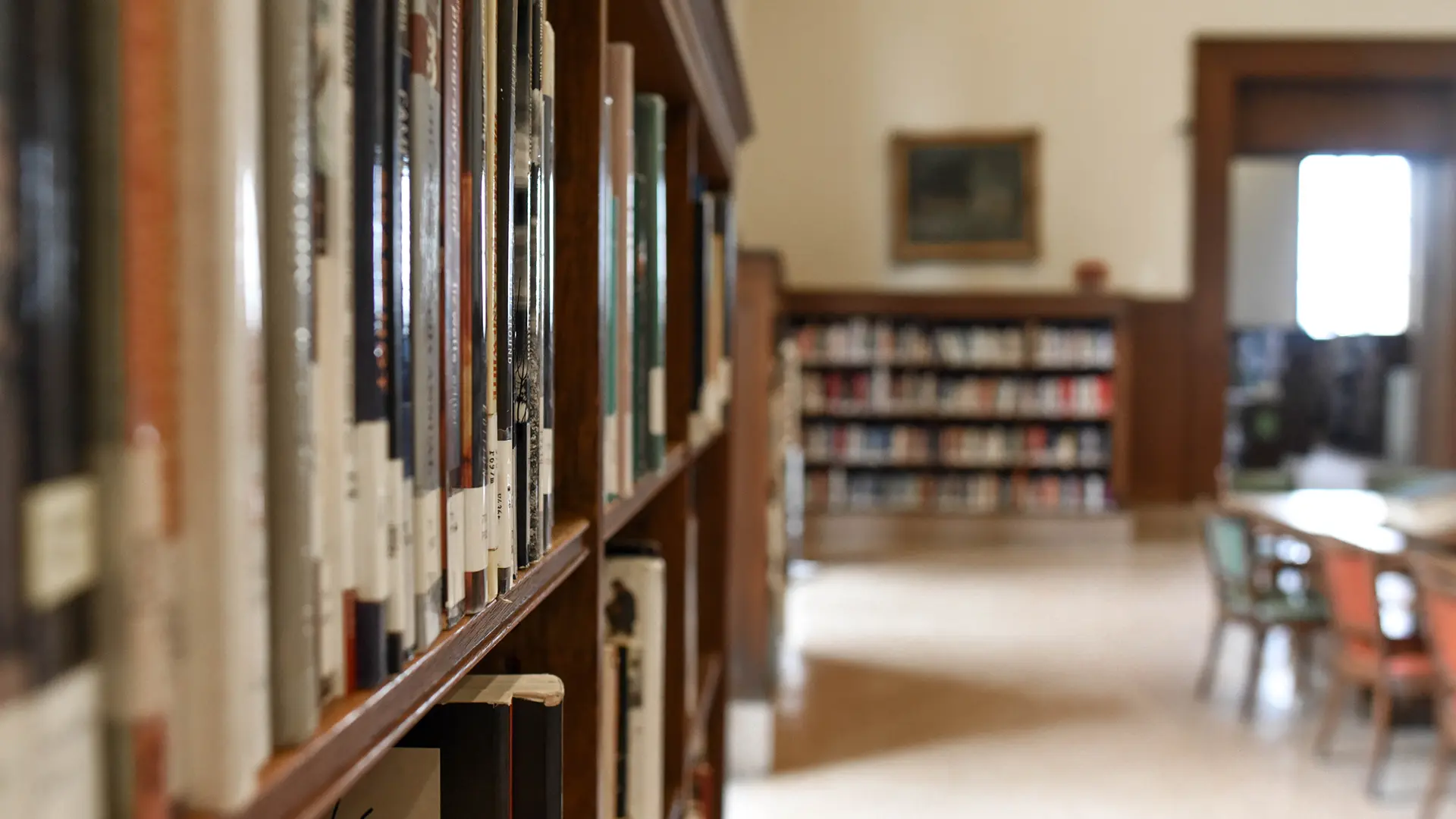 Image of inside of a library with books going out of focus and another bookshelf behind it