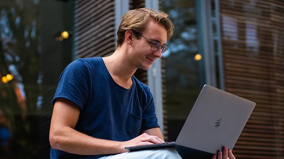 Image of a man wearing glasses looking at a laptop.