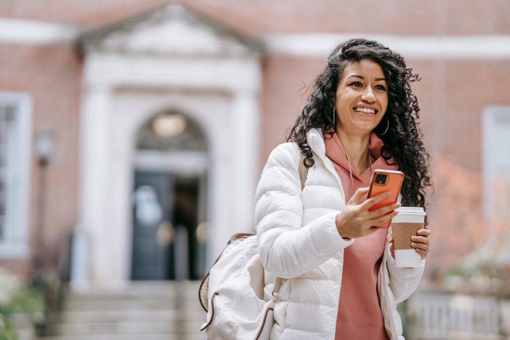 Female student smiling while looking at cell phone.