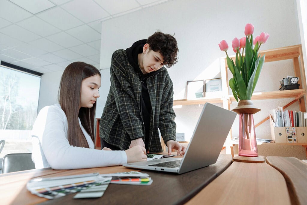 Male and female student looking at a laptop