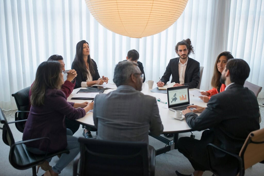 Group of coworkers gather around a circular table.