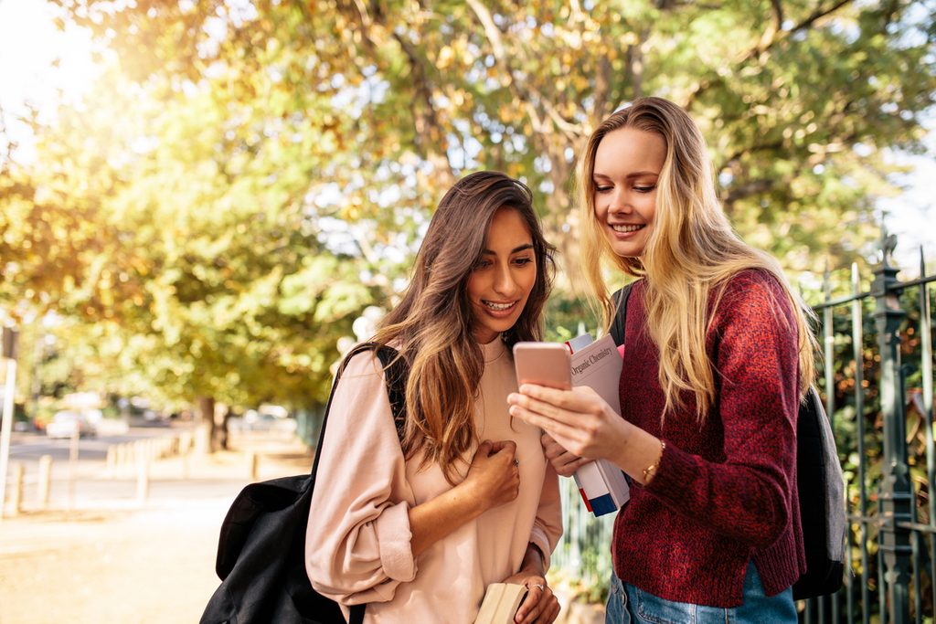 High school  students exploring a college through a virtual campus tour on a phone